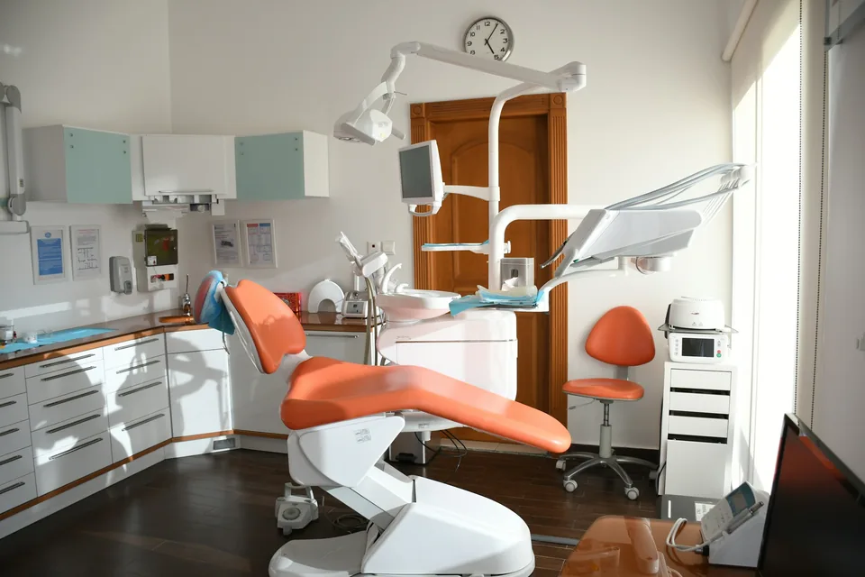 A bright dental office with an orange treatment chair