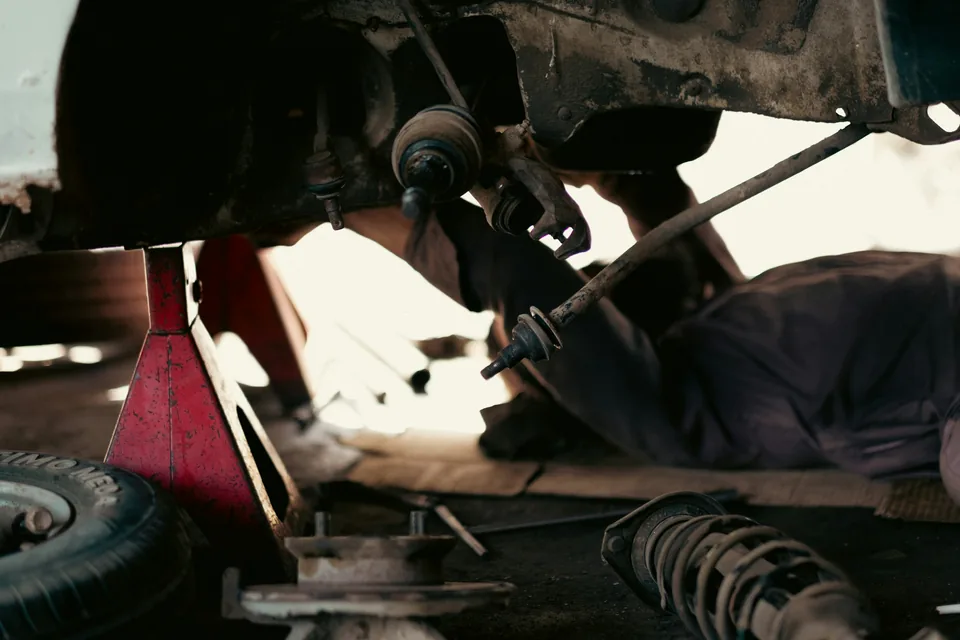 A mechanic working beneath a car on a jack stand