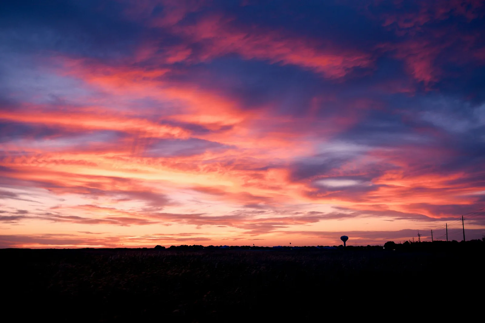 A wide sky glowing orange and violet over a dark flat horizon